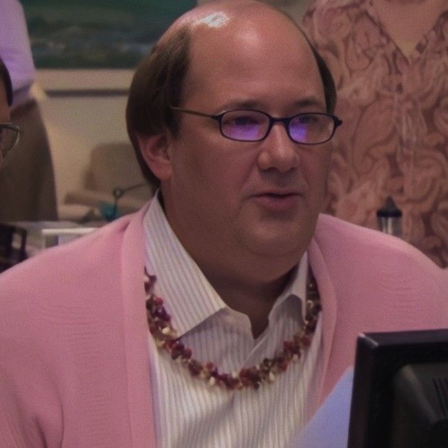 a man wearing glasses and a pink jacket is looking at something on the computer screen