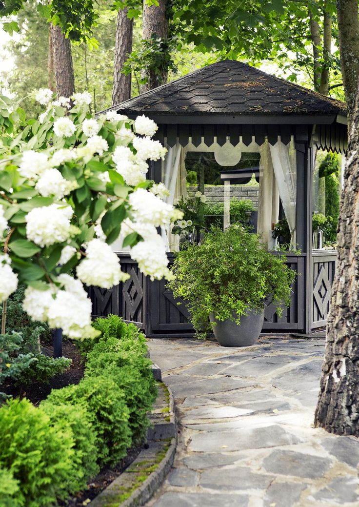 a gazebo surrounded by white flowers and trees