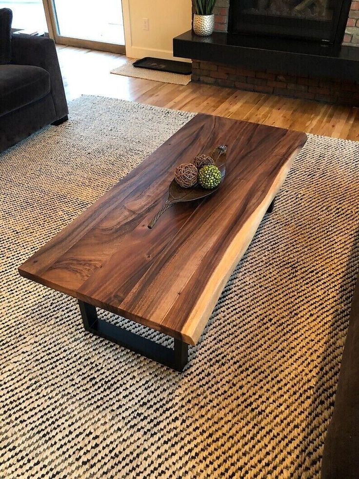 a wooden table sitting on top of a rug in front of a couch and fireplace