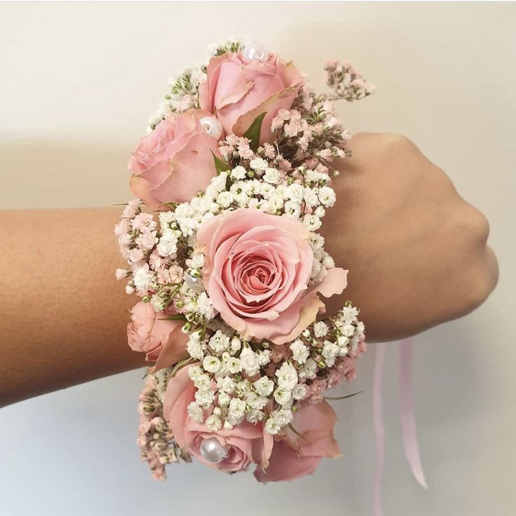 a woman's arm holding a bouquet of pink roses and baby's breath