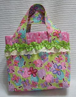 a pink and green bag with flowers on the front is sitting on a white surface