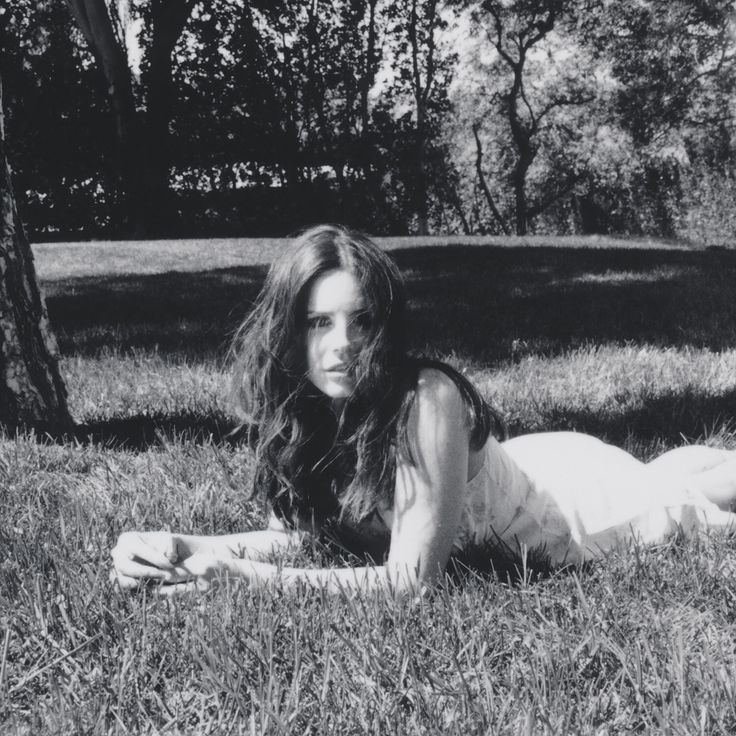 a woman laying on the grass in front of a tree