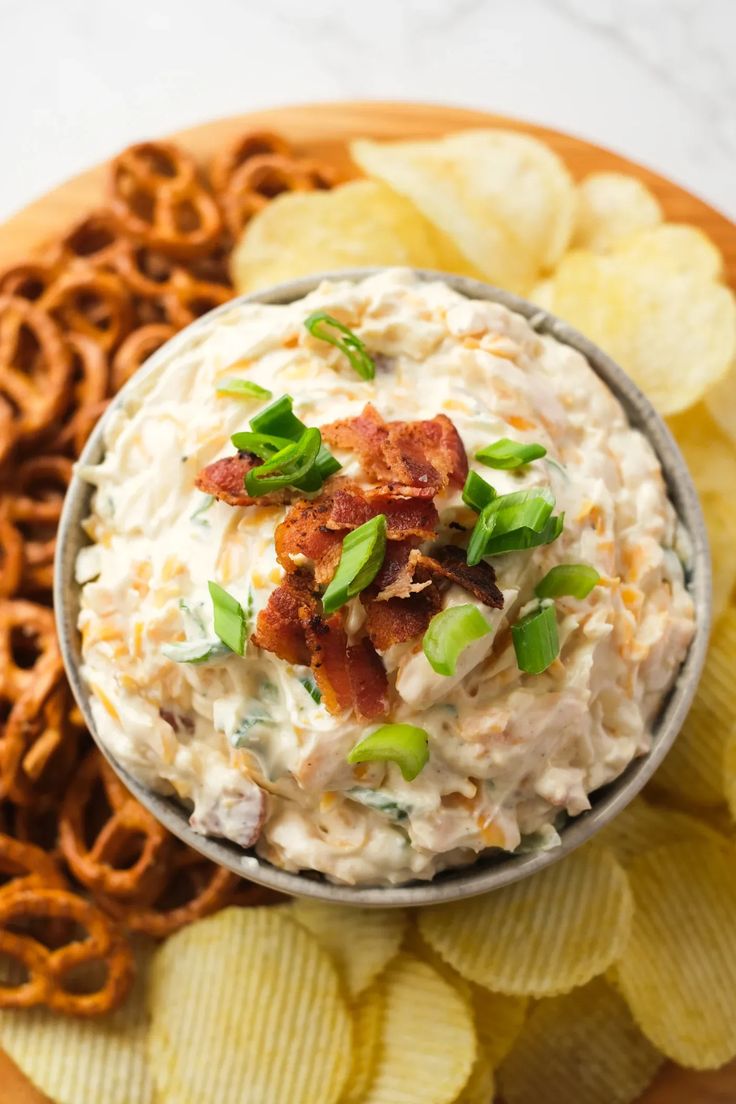 a bowl of dip surrounded by pretzels and crackers