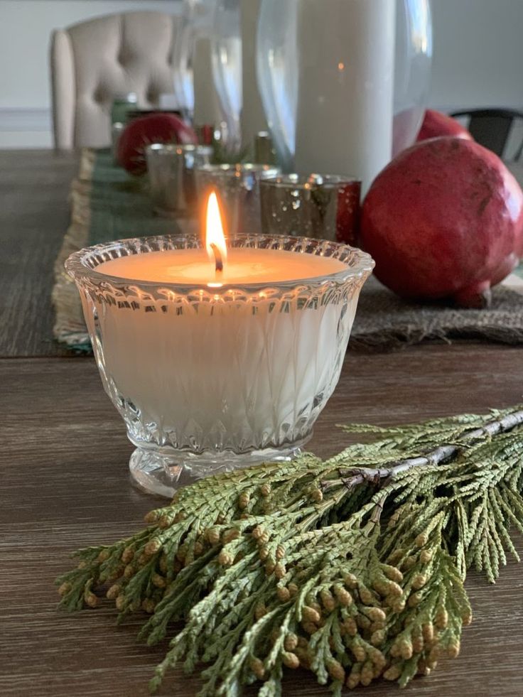 a lit candle sitting on top of a table next to pine cones and other christmas decorations