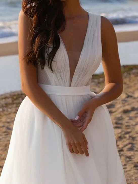 a woman standing on top of a beach next to the ocean wearing a white dress