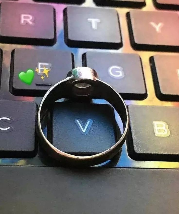 a ring sitting on top of a computer keyboard with the word love spelled below it