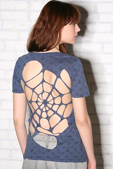 a woman standing in front of a brick wall wearing a t - shirt with a spider web design on it