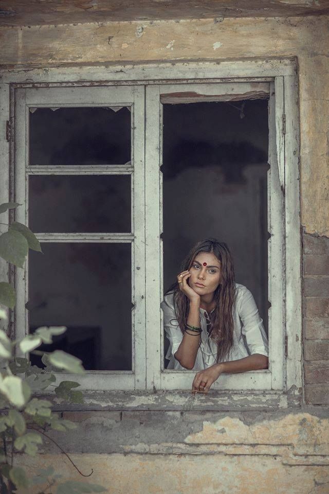 a woman sitting in a window sill with her hand on her face