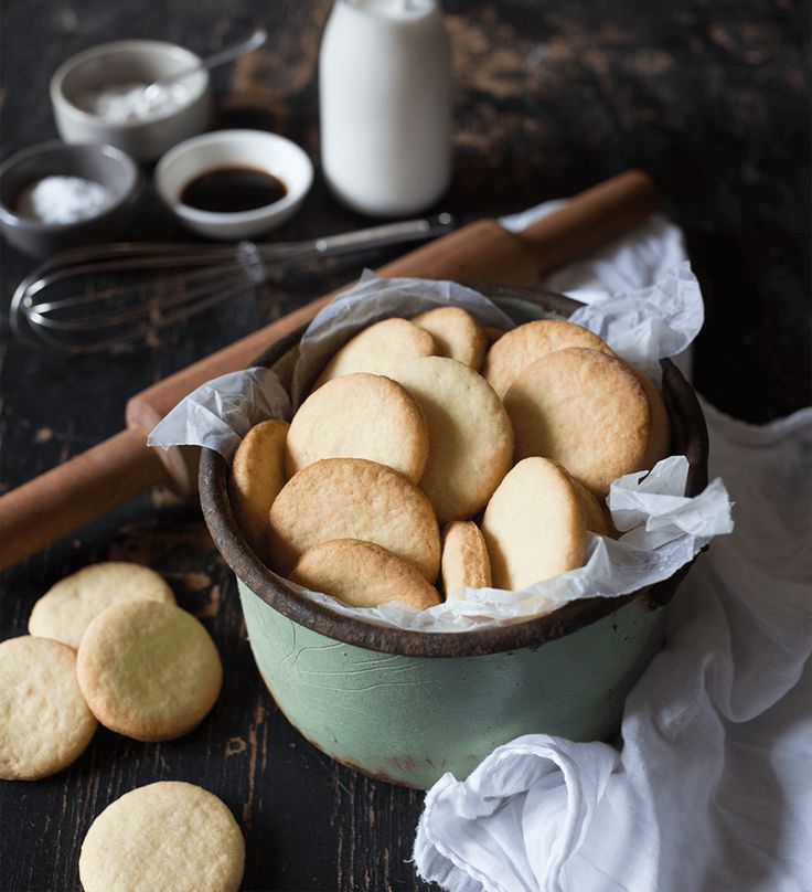 a bowl full of cookies next to some sugar