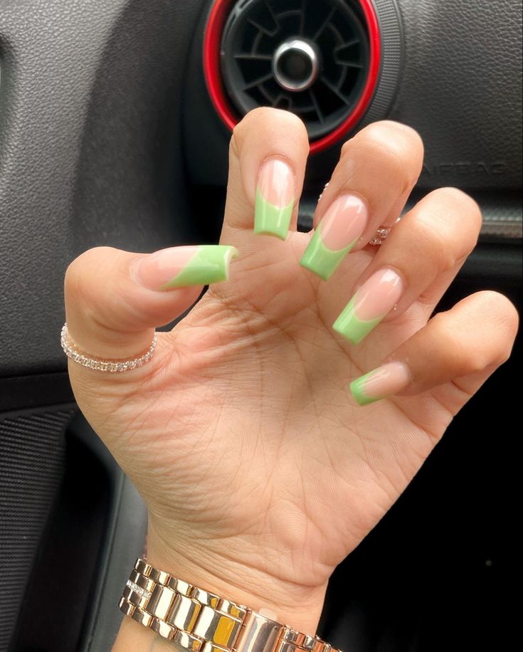 a woman's hand with green nail polish holding up her fingers in the car