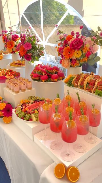 an assortment of food is displayed on a white tablecloth with oranges and pink flowers