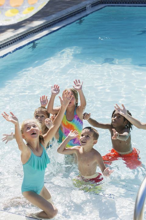 children playing in the pool with their hands up