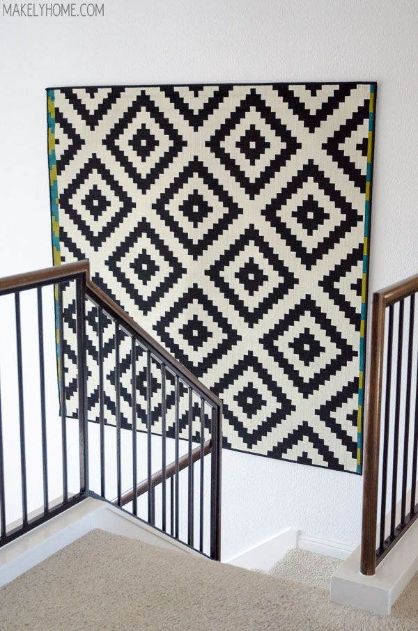 a black and white rug hanging on the wall next to a banister with metal handrails