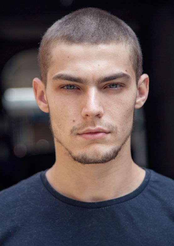 a close up of a person wearing a black t - shirt and looking at the camera