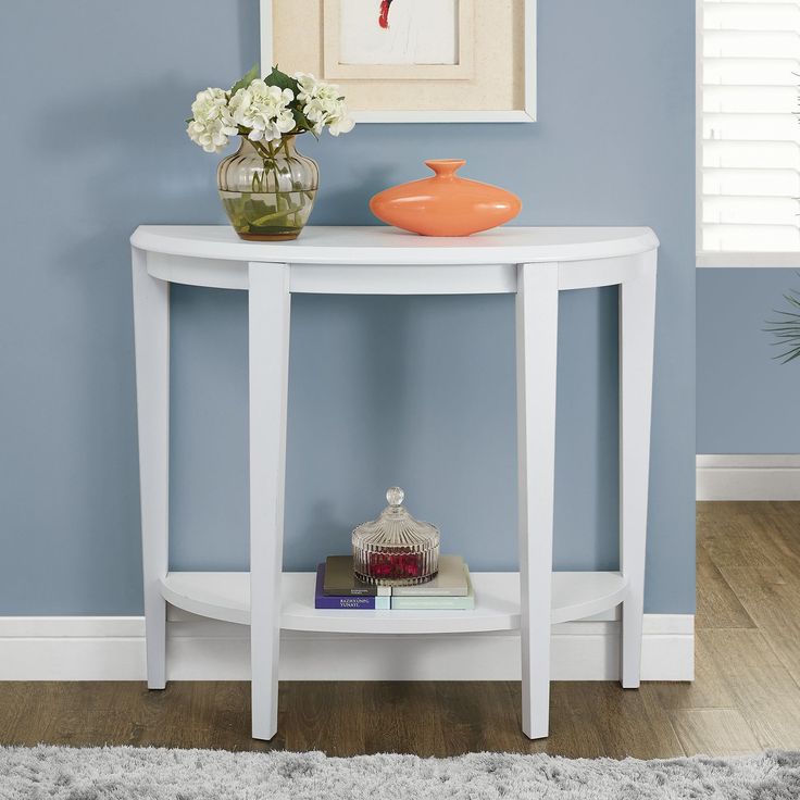 a white table with a vase on top of it and books in front of it