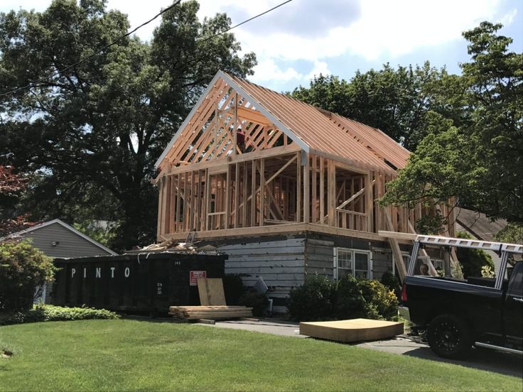 a house under construction with a truck parked in front of it and the roof is up