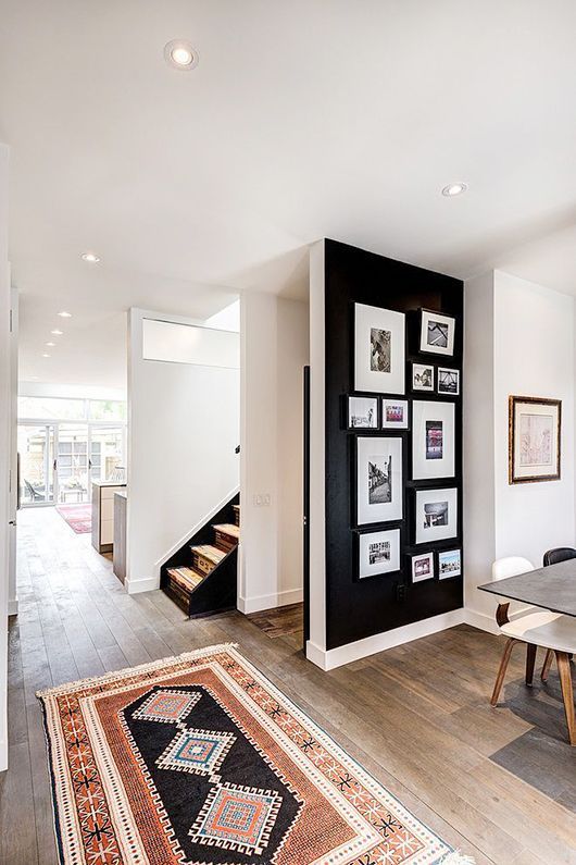 a dining room table with chairs and pictures on the wall behind it in front of a staircase