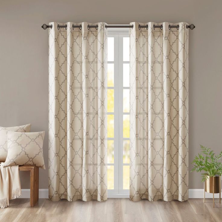 a living room with white curtains and wood flooring in front of a large window