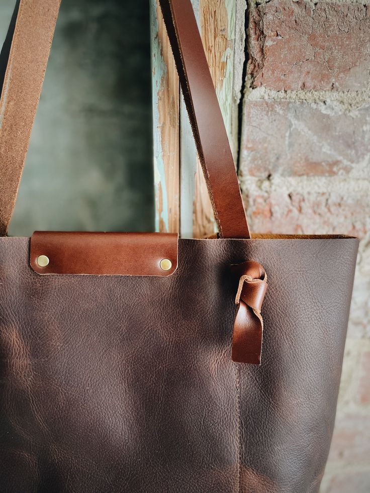 Looking for something deep and rustic? Here’s your dream bag for all day, every day. With a large interior pocket and adjustable knotted straps you’re good to go. Optional snap closure. 15” w by 14” h by 4” Everyday Bucket Tote Bag With Snap Closure, Leather Bucket Bag With Snap Closure For Everyday, Rectangular Hobo Bag With Snap Closure For Everyday, Everyday Shoulder Bag With Snap Closure And Double Handle, Rustic Bags With Leather Lining For Everyday Use, Everyday Rectangular Bucket Bag With Brass Hardware, Leather Bucket Bag With Snap Closure In Tote Shape, Rustic Rectangular Shoulder Bag For Everyday Use, Everyday Leather Satchel With Snap Closure