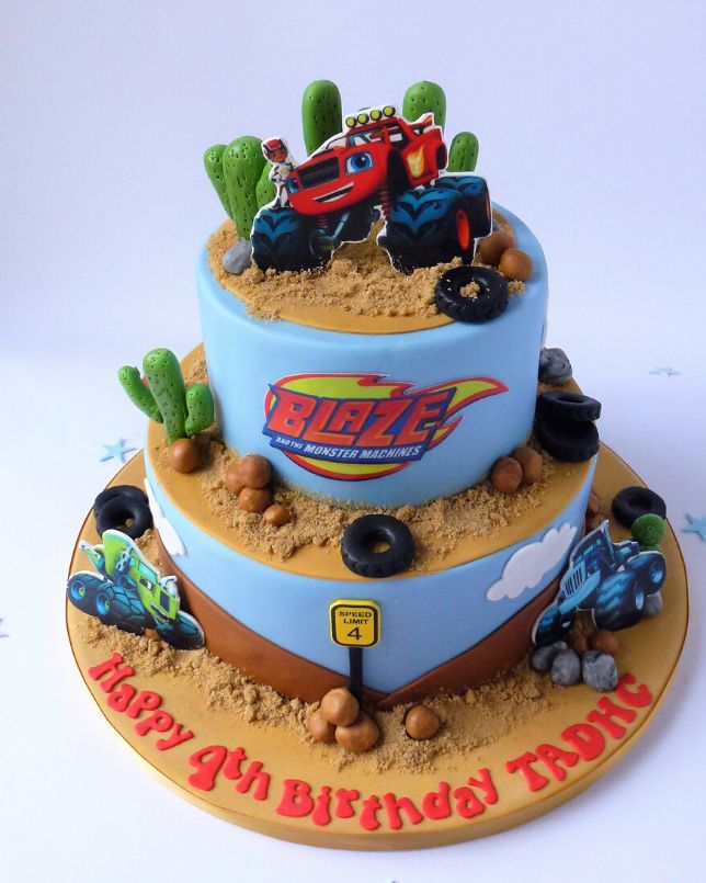 a three tiered birthday cake with monster trucks on it