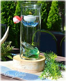 a vase filled with water sitting on top of a wooden table next to plants and candles