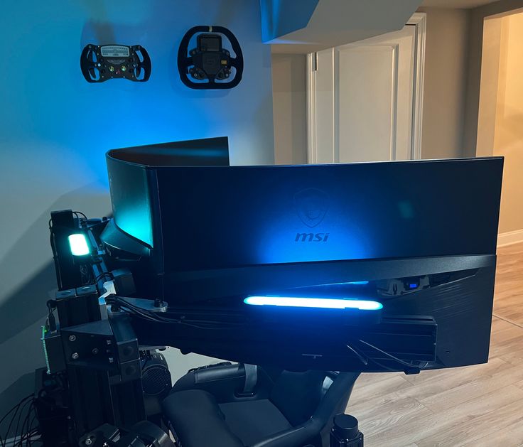 a computer monitor sitting on top of a desk in front of a blue wall with lights