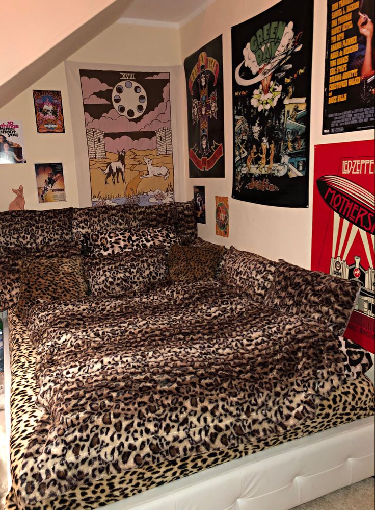 a leopard print comforter on a bed in a room with posters and pictures above it