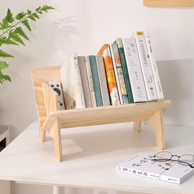 there is a wooden book stand with books on it next to a potted plant