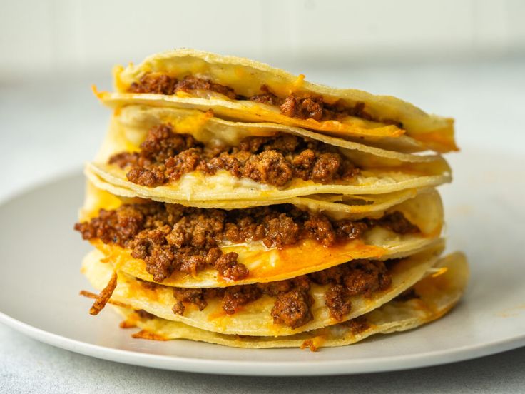 a stack of cheese and ground beef quesadillas on a white plate