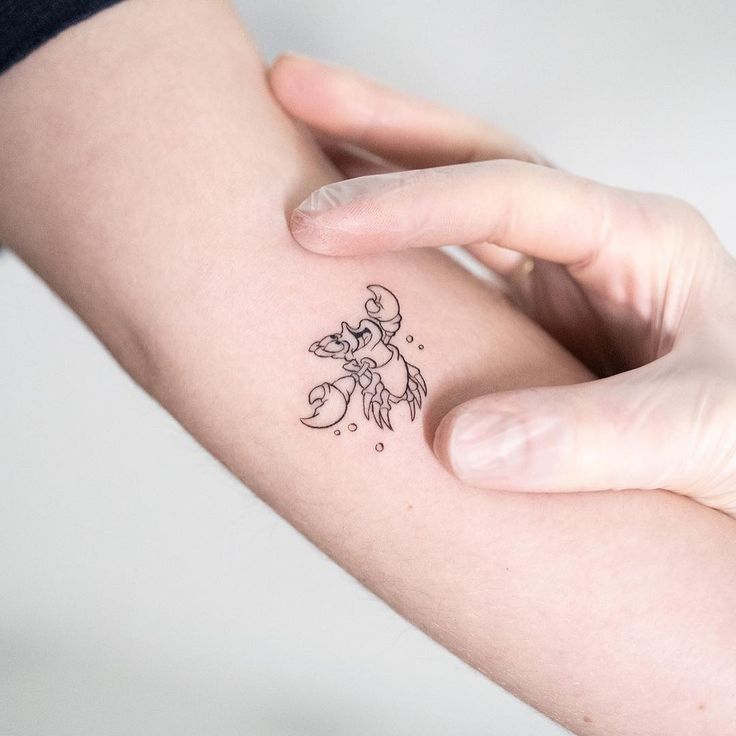 a person holding their arm with a small tattoo on it