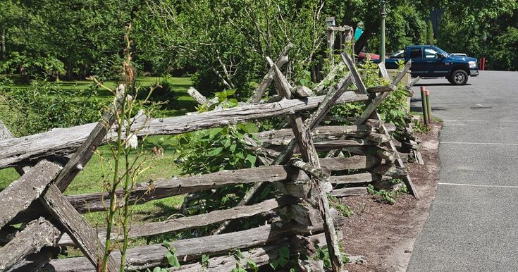 an old wooden fence sitting on the side of a road