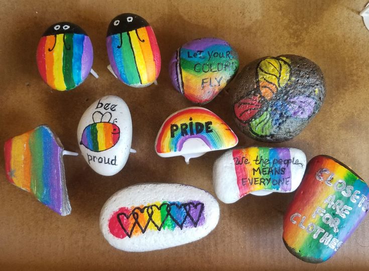 painted rocks that say pride and have different designs on them with words written in rainbow colors