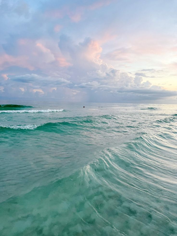 an ocean with waves and clouds in the sky