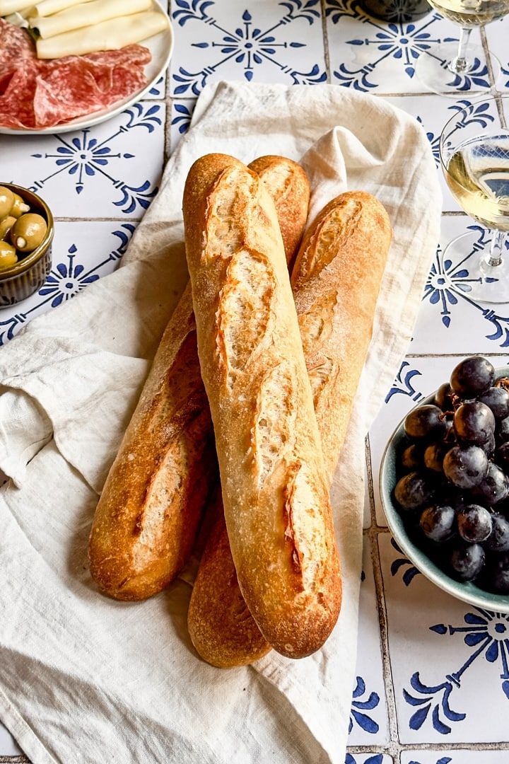 two loaves of bread sitting on top of a table next to bowls of olives