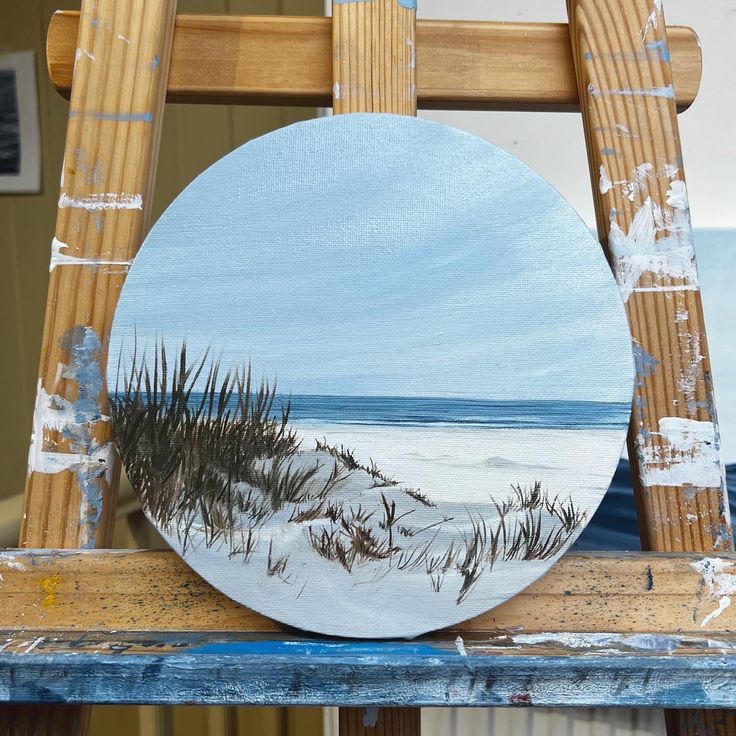 an easel with a painting on top of it and the ocean in the background