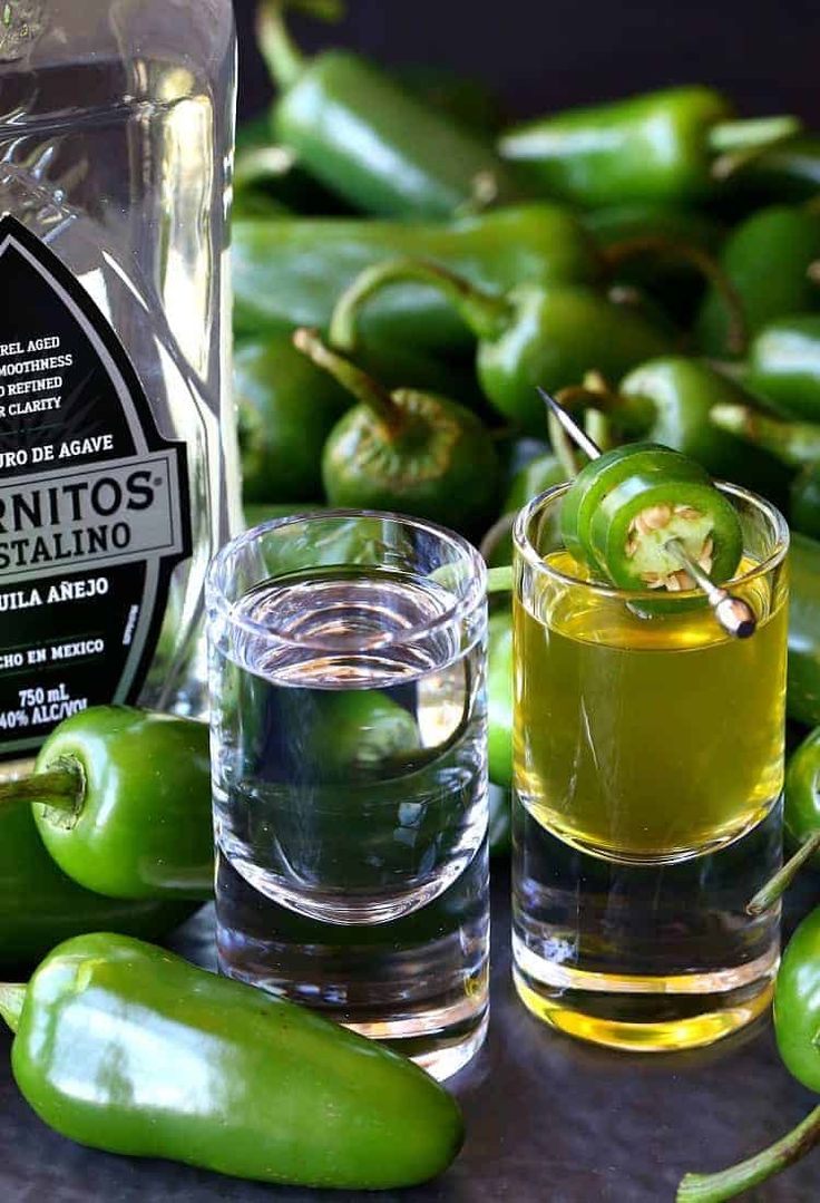 some green peppers sitting on top of a table next to a bottle and two glasses