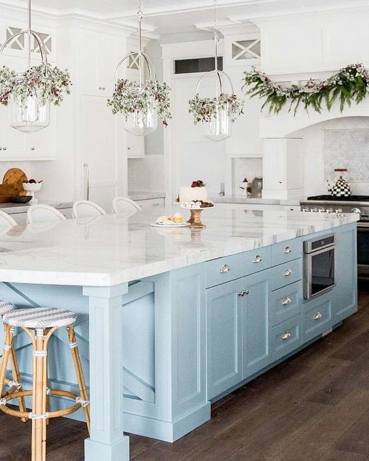 a large kitchen with blue cabinets and white counter tops is decorated with christmas greenery