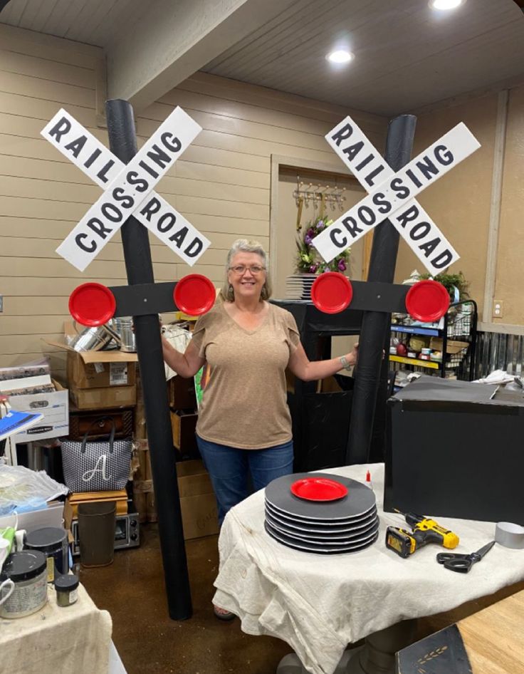 a woman is standing next to some railroad crossing signs in a room with other items