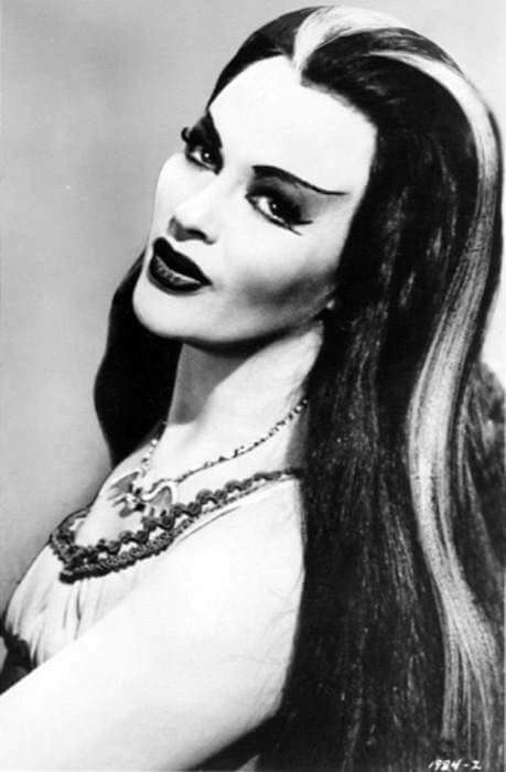 a black and white photo of a woman with long hair, wearing an evil makeup look