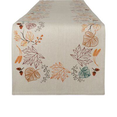 a table runner with leaves on it and an orange, green, yellow and blue design