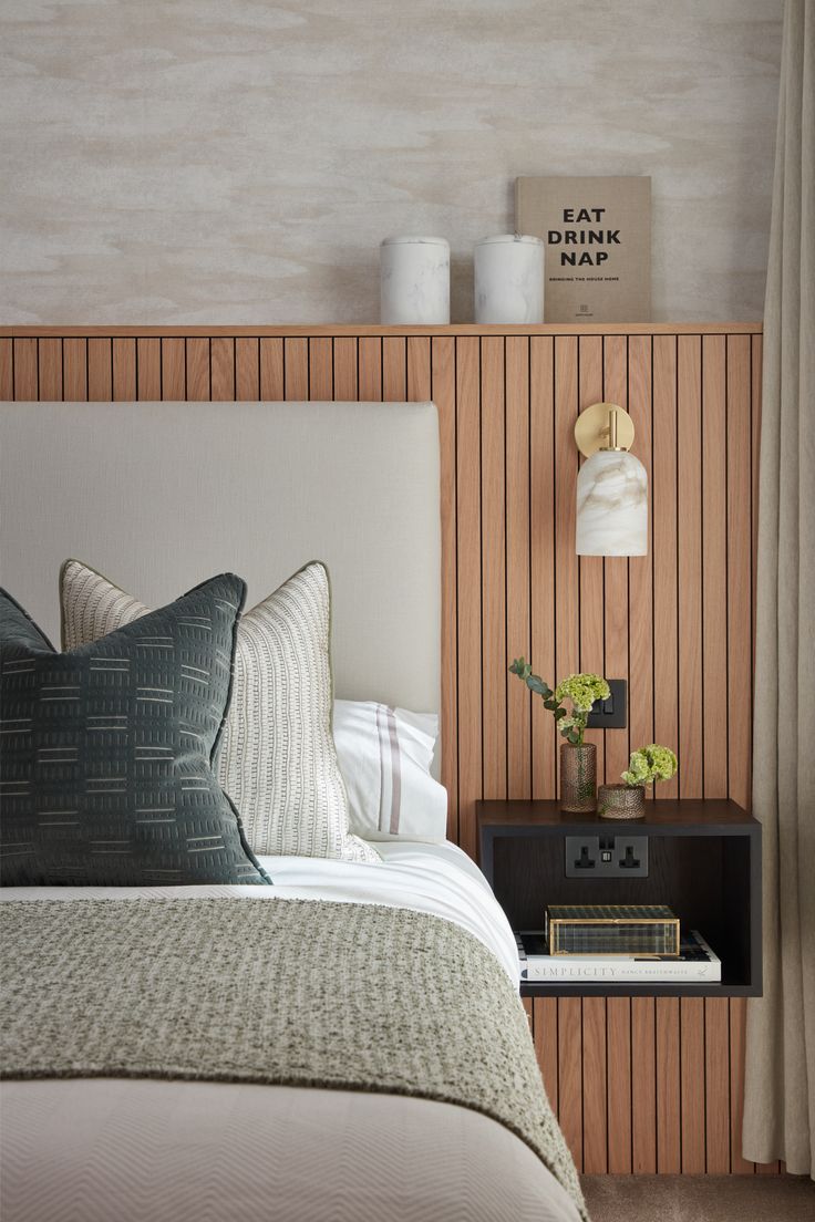 a bed with two pillows on top of it next to a night stand and lamp