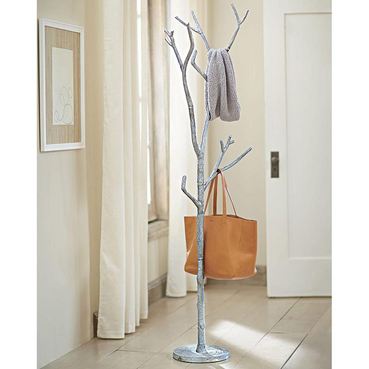 a coat tree in the corner of a room with two purses on it and a handbag next to it