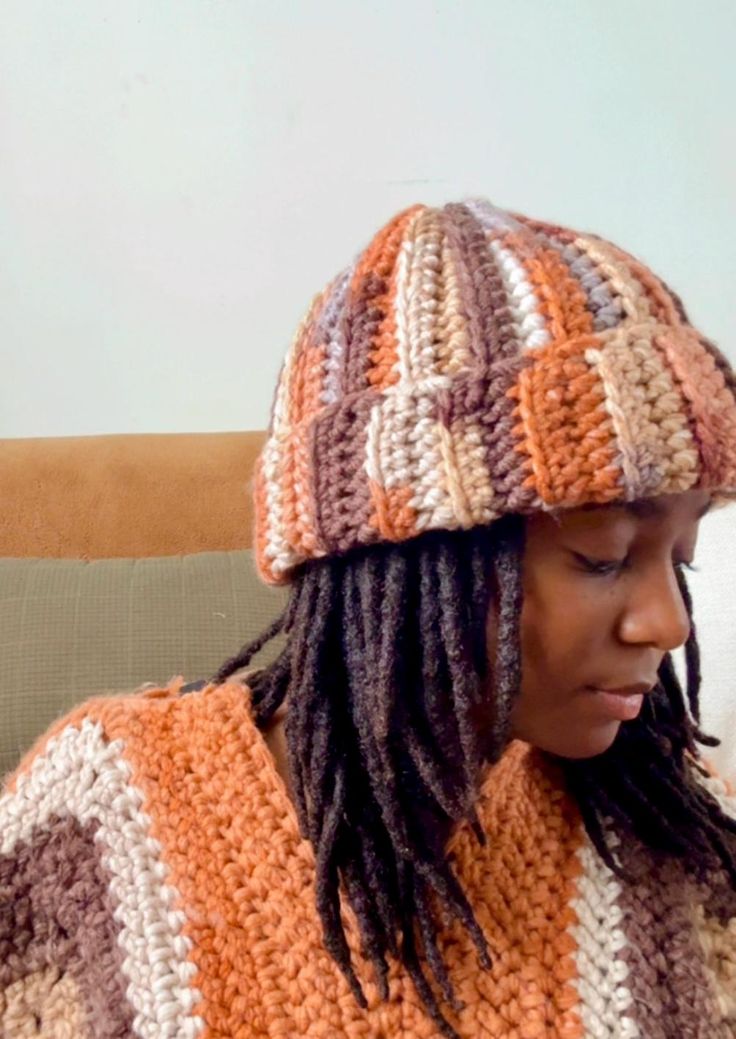 a woman sitting on a couch wearing a knitted hat