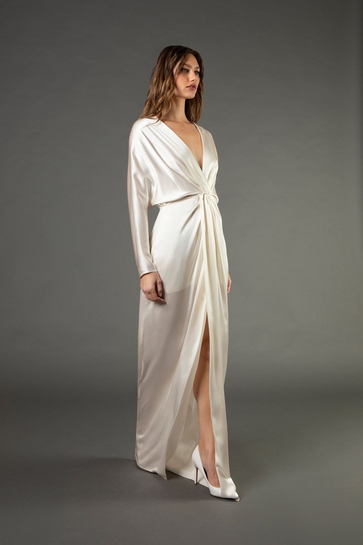 a woman wearing a white dress with long sleeves and an asymmetric wrap around the waist