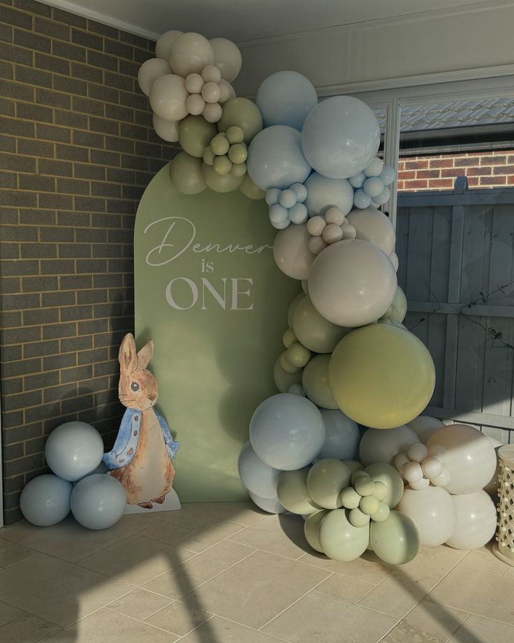 a balloon arch with balloons on it and a bunny statue next to the sign that says, dance one