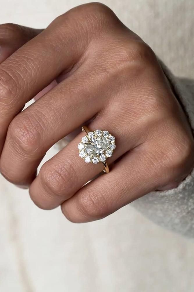 a woman's hand with a diamond ring on top of her finger and the other hand holding an engagement ring