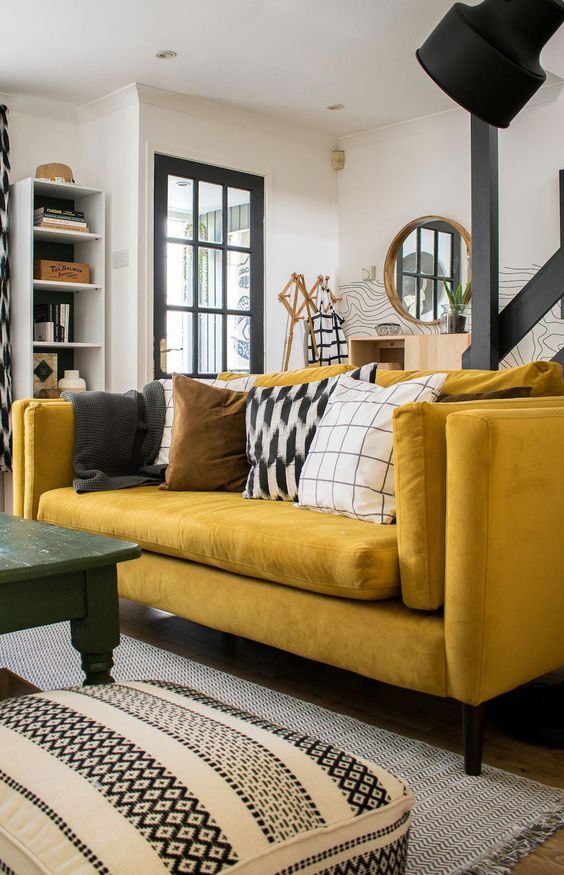 a living room filled with yellow couches and black and white rugs on top of a hard wood floor