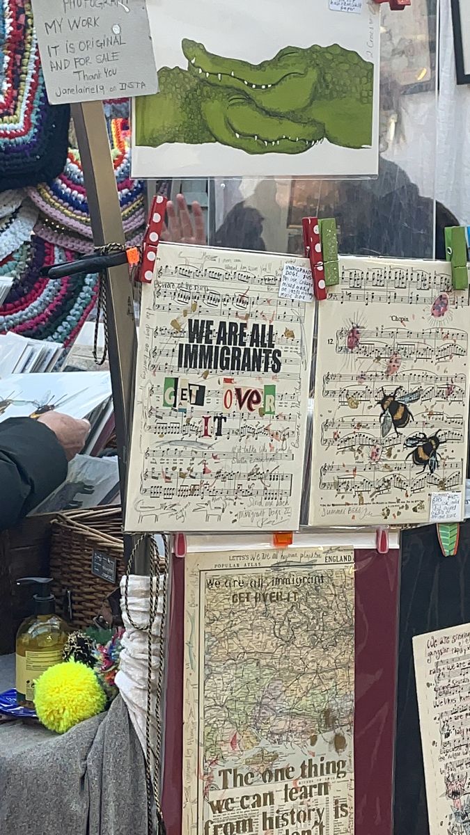 there are many posters on display at the market with words and pictures hanging from them