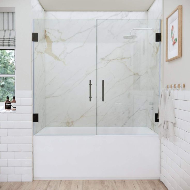 a bathroom with white walls and wood flooring has a glass shower door that is open to the outside