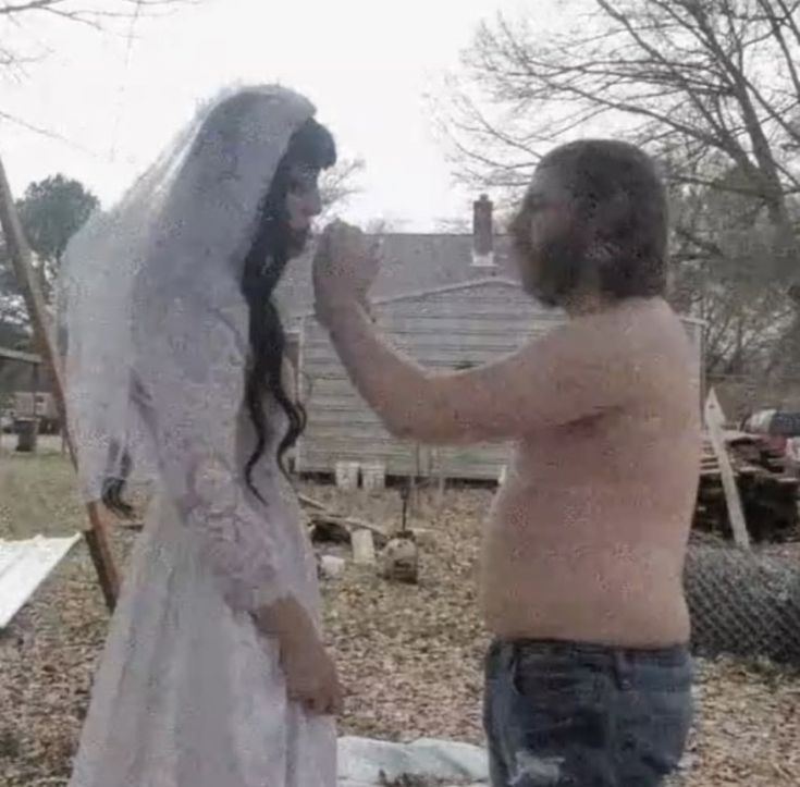 a man and woman dressed in wedding attire standing next to each other on the ground